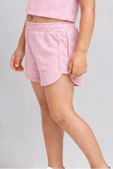 Young girl wearing a pink outfit with ruffled sleeves on a gray background