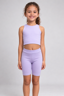 Young girl wearing a light purple athletic outfit on a gray background